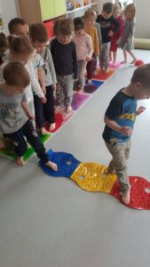 Dzieci stymulują zmysł dotyku i równowagi spacerując po kosmicznej ścieżce sensorycznej.