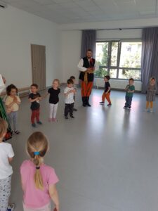 Dzieci stoją w kole i uczą się jak tańczyć poloneza.