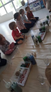 Dzieci uważnie obserwują, jak przygotować świeczkę.