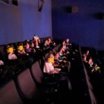 dzieci siedza na widowni w kinie